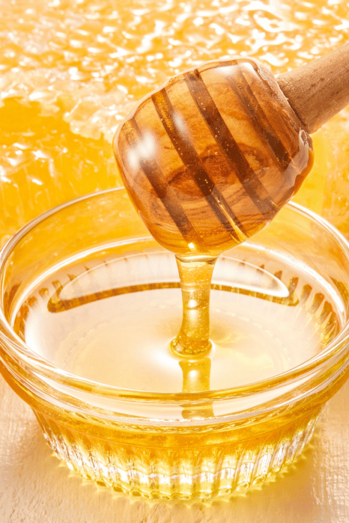Golden honey dripping from a wooden dipper with a clear glass dropper bottle – natural hydrating glow serum | slincaresolutions.in