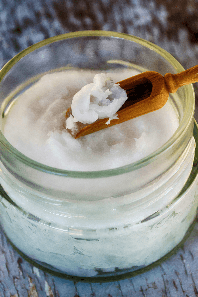 Thick virgin coconut oil on a wooden spoon – moisturizing texture for skincare | skincaresolutions.in